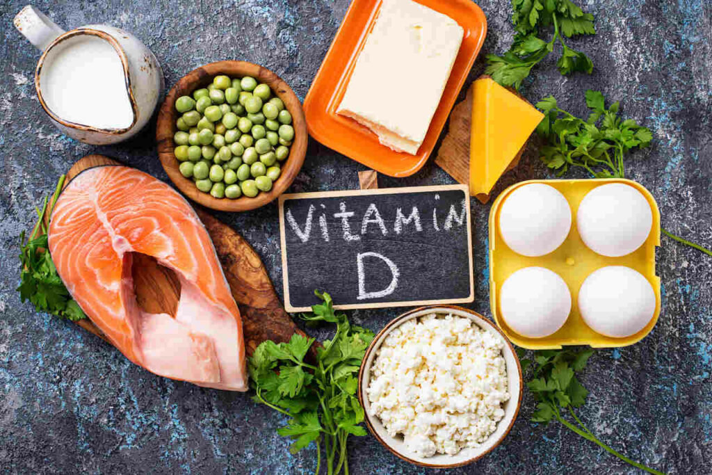 Alimentos ricos em vitamina D: salmão, ovos, leite, queijo e ervilhas sobre mesa rústica com destaque para nutrientes essenciais.