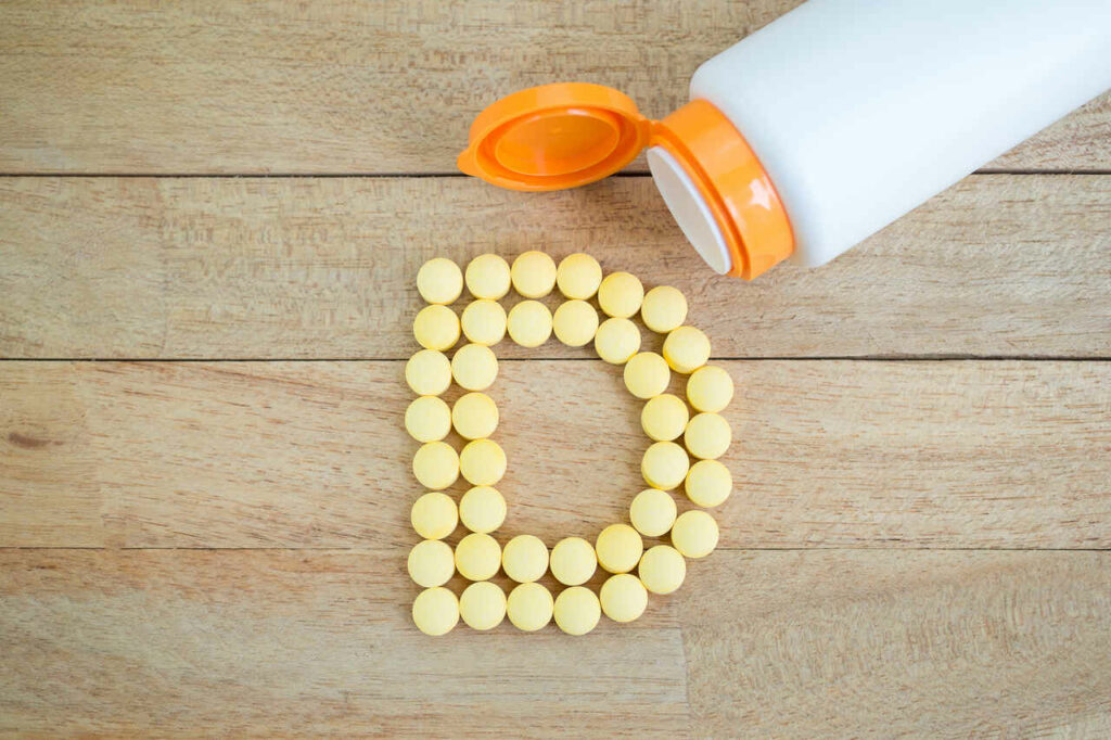 Cápsulas de vitamina D formando a letra D em conceito de suplementação e saúde imunológica.